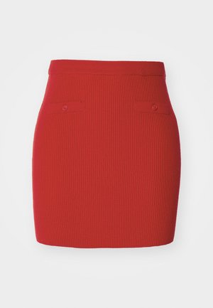 Roter gerippter Strickrock mit taillierter Passform, der zwei kleine geknöpfte Taschen auf der Vorderseite und einen glatten Taillenbund aufweist.
