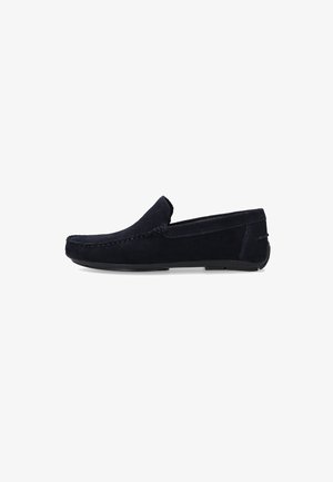 Heren loafer van marineblauw suède met instapmodel, zwarte rubberen zool en zichtbare stiksel langs de randen, afgebeeld op een witte achtergrond.