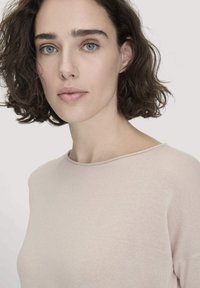 Hellsrosanes Rundhalsoberteil, taillierte Passform, weiche Textur, gerippte Akzente am Kragen, mit kurzen Ärmeln und glatter Oberfläche.