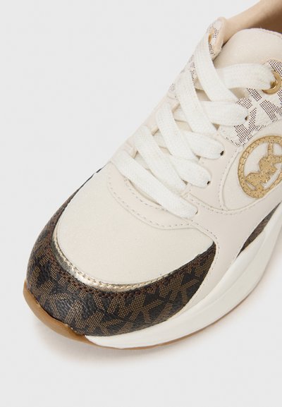 Las zapatillas presentan un upper texturizado blanco, acentos con un patrón marrón, branding en dorado y una suela blanca gruesa con una suela exterior de goma marrón clara.