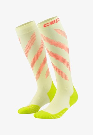 Light yellow knee-high compression socks with bright pink diagonal stripes and neon yellow accents on toes and heels.