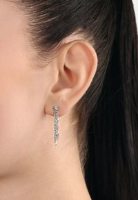 Pendientes de plata colgantes con un diseño de cadena trenzada y un pequeño stud, mostrando una superficie lisa y reflectante.