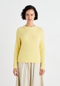 Light yellow, soft knit sweater with long sleeves and a crew neckline; features a slightly fitted shape and ribbed hem and cuffs.