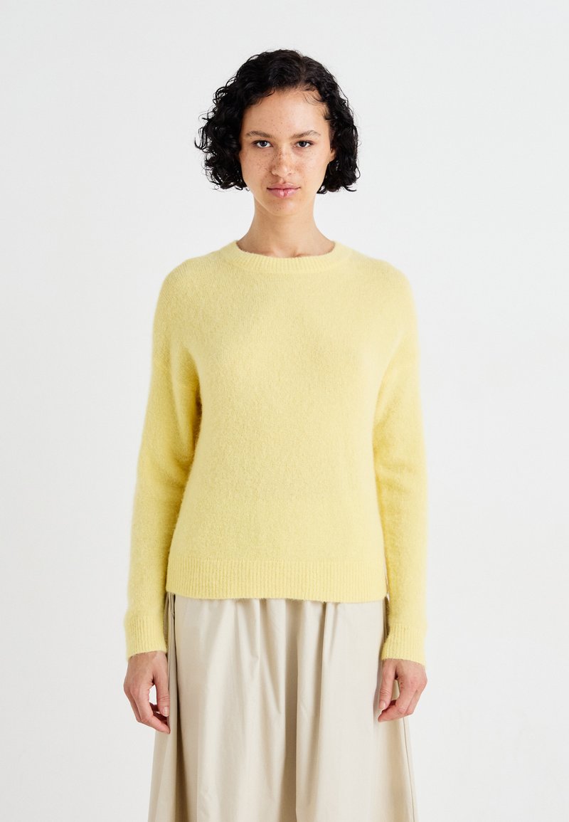Light yellow, soft knit sweater with long sleeves and a crew neckline; features a slightly fitted shape and ribbed hem and cuffs.