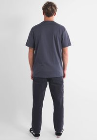 T-shirt à manches courtes, col rond, en coton gris foncé, associé à un pantalon cargo noir. Design simple avec une coupe décontractée et sans motifs visibles.