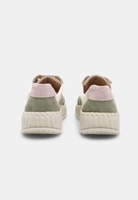 Sneakers in suede verde e beige con suola spessa e texture. Presentano un accento rosa sul tallone e un rivestimento interno morbido.