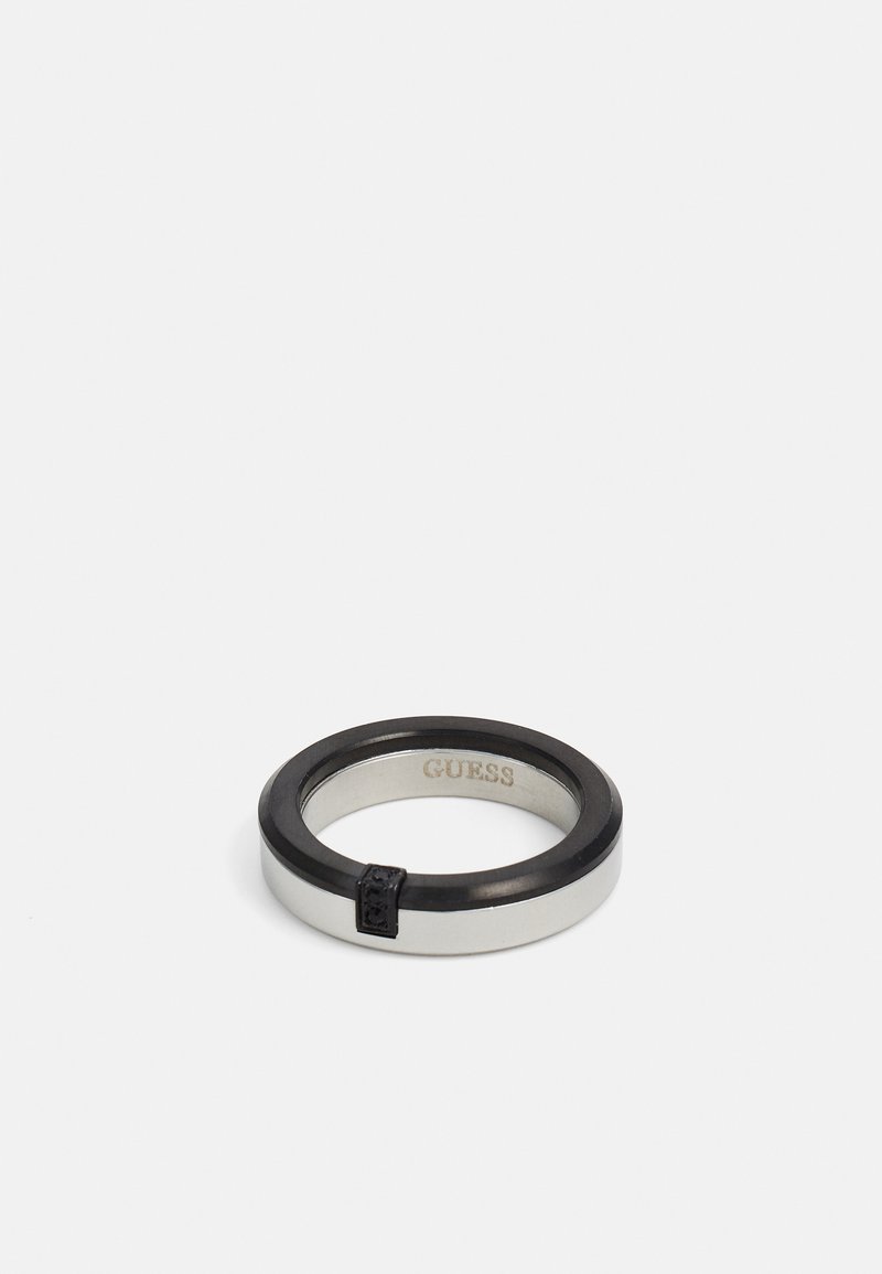 Silver and black ring with a smooth finish, featuring a thin black band and a small accent detail on the side. Engraved "GUESS" inside.