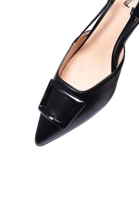 Scarpa slingback nera a punta con una lucente fibbia quadrata, esterno in pelle liscia e interno nudo. Presenta delicate cinghie alla caviglia.