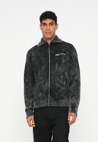 Fekete cipzáros dzseki kordbársony anyagból, texturált felülettel. Magas gallérral, bordázott mandzsettákkal és a mellkason lévő "KARL LAGERFELD JEANS" logóval rendelkezik.