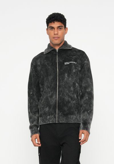 Veste zippée noire en velours côtelé avec une finition texturée. Dotée d'un col montant, de poignets côtelés et du logo "KARL LAGERFELD JEANS" sur la poitrine.