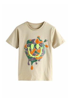 T-shirt beige a maniche corte con una macchia di camuffamento colorato e una grafica di faccina sorridente gocciolante di verde neon sul davanti.