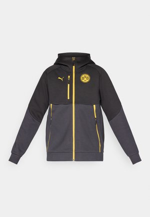 Puma hooded jacket in black and grey with yellow accents. Features zip pockets, a logo patch, and ribbed cuffs. Made from a soft, durable material.