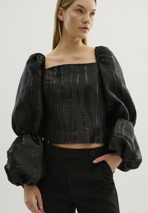 Černý krátký top s oversized, texturovanými balónovými rukávy, s vertikálními pruhy, čtvercovým výstřihem a hladkým saténovým povrchem.