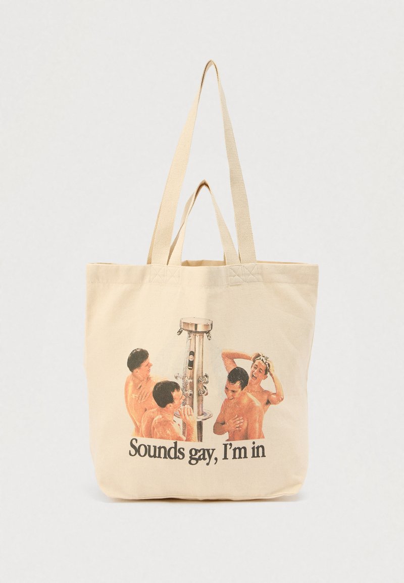Τσάντα ώμου από καμβά, μπεζ χρώματος, με απεικόνιση τεσσάρων ανδρών που κάνουν μπάνιο με μεταλλικό ντους, το κείμενο γράφει "Ακούγεται γκέι, συμμετέχω."