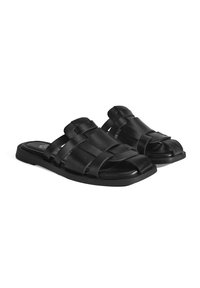 Sandales noires avec des brides tressées, design ouvert à l'avant, semelle plate et finition lisse. Légères avec un look minimaliste et moderne.
