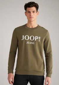 Felpa verde oliva con maniche lunghe, collo a giro e testo "JOOP! JEANS" in bianco. Tessuto liscio, design aderente e polsini a costine.