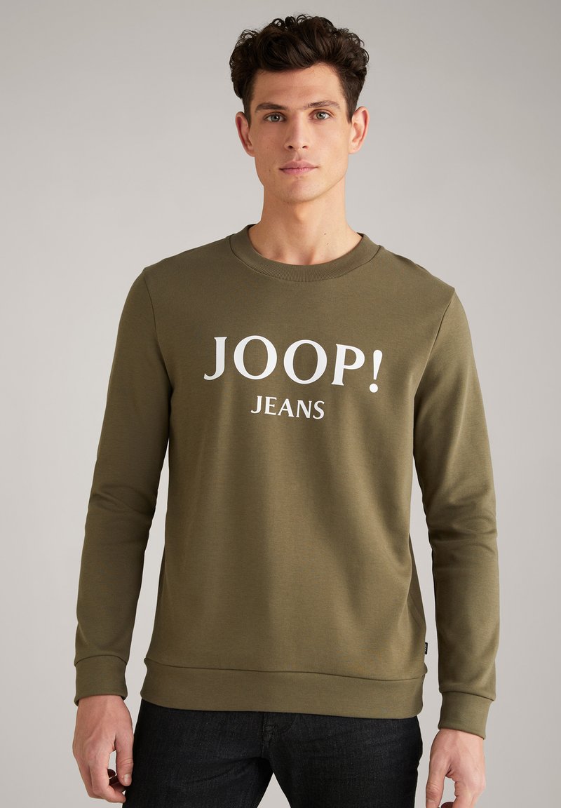 Felpa verde oliva con maniche lunghe, collo a giro e testo "JOOP! JEANS" in bianco. Tessuto liscio, design aderente e polsini a costine.