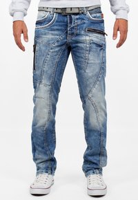 Jeans in denim blu chiaro con una vestibilità slim, caratterizzati da pannelli asimmetrici, numerose tasche con zip e dettagli di cucitura a contrasto.