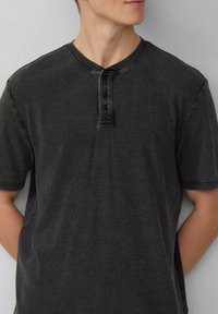 Graues Kurzarm-Henley-Shirt aus strukturiertem Stoff mit drei Knöpfen am Kragen, das ein einfaches, lässiges Design bietet.