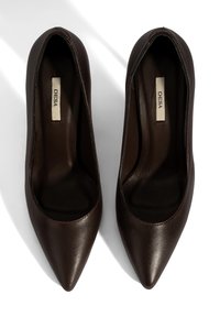 Bruine leren high heels met een puntige neus, een gladde textuur en een slank ontwerp. Het interieur heeft een label met "DESA" erop gedrukt.