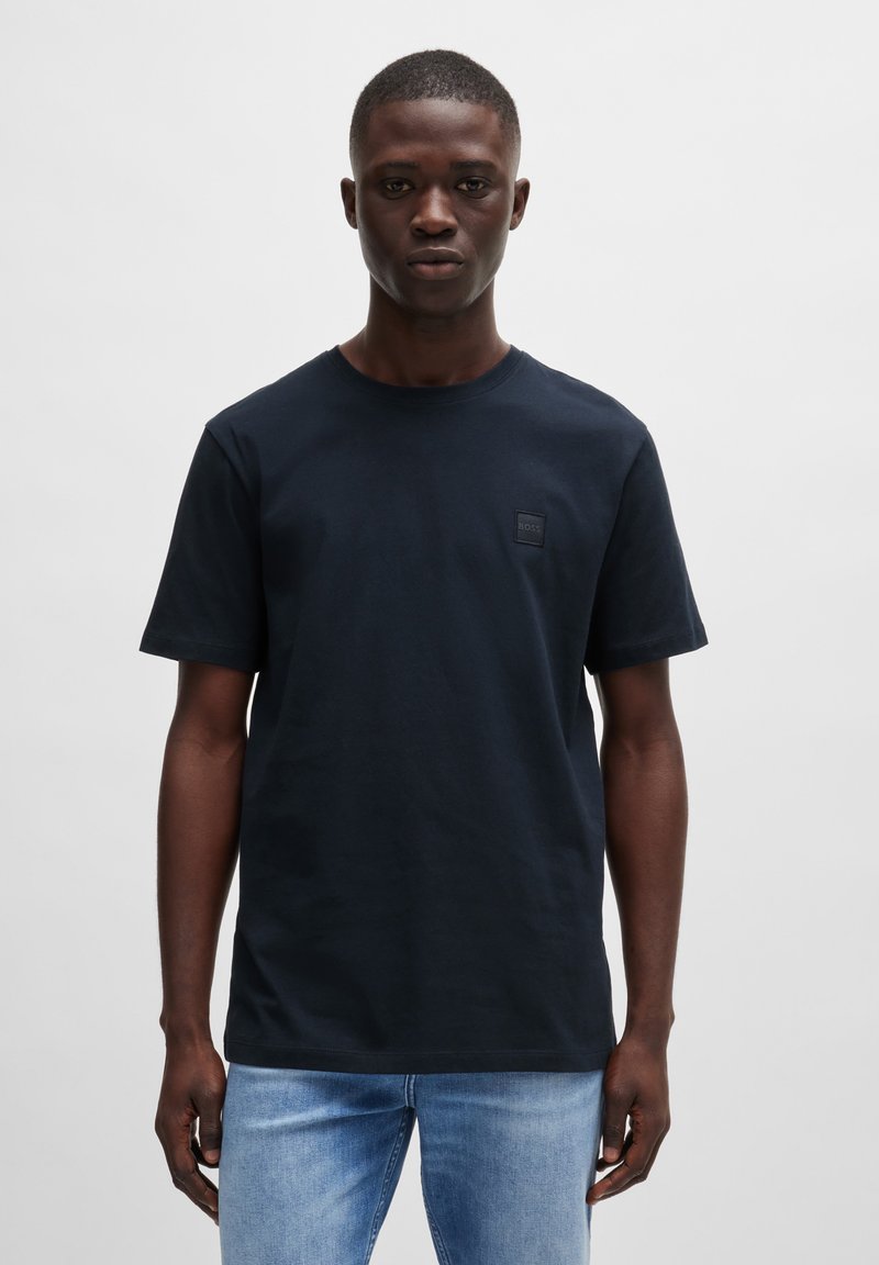 Navy T-shirt in cotton with a crew neck, short sleeves, and a square logo patch on the chest. Smooth texture, relaxed fit.