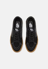 Crne suede tenisice s bijelim šavovima, okrugli vrh, vezanje s vezicama i gumeni potplat; s Vans logotipom na jeziku.