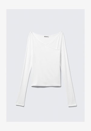 Valge pika varrukaga topp, millel on ristatud disain ja tasku. Valmistatud siledast ja venivast kangast. Lõige on kaunis ja lõdva sobivusega.