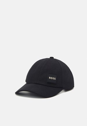 Schwarze Baseballkappe mit gebogenem Schirm und einem quadratischen Logo-Patch mit der Aufschrift "BOSS" auf dem Frontpanel, vor einfachem hellem Hintergrund.