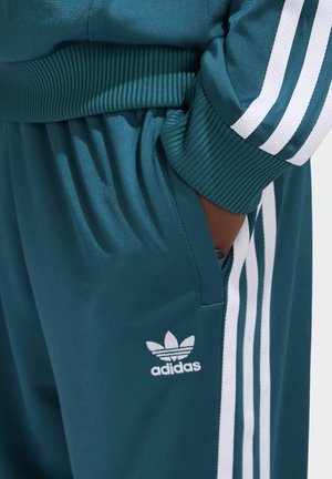 Teal sportbroeken met geribbelde tailleband, witte drie-streep patroon aan de zijkanten en klein wit Adidas-logo op de dij.