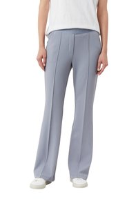 Jasnoszare, rozkloszowane spodnie wykonane z gładkiej tkaniny, z wysokim stanem i ozdobnymi szwami z przodu. W połączeniu z białymi trampkami.