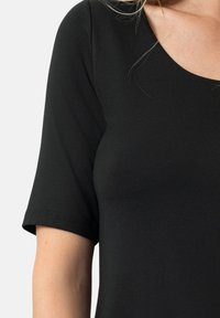 Sort kortærmet skjorte lavet af blødt, elastisk stof. Har en rund halsudskæring og en tætsiddende silhuet for komfort og bevægelsesfrihed.