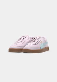 Světlé růžové semišové tenisky s tyrkysovými akcenty, vybavené gumovou podrážkou, plochými tkaničkami a zlatým logem na boku.