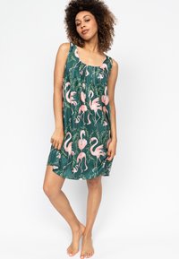 Sukienka w flamingi w zielonym materiale. Bez rękawów, o swobodnym kroju, z różowymi motywami flamingów i liściastymi akcentami w całej długości.