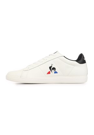 White low-top sneaker with black heel, lace-up design, and a black rooster logo above red and blue shapes on the side.
