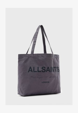 Pelēka auduma tote soma ar divām siksnām, uz kuras ir redzams uzraksts "ALLSAINTS" un mazāks teksts zemāk, gluda tekstūra.