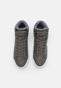 Zapatillas altas grises hechas de cuero suave con un forro de felpa gris texturizada, con suelas de goma blanca y un diseño de cordones tradicional.