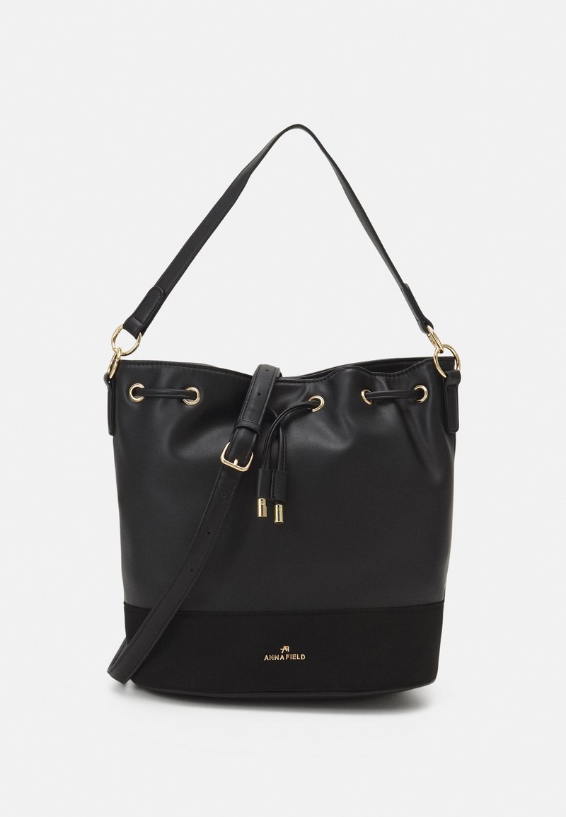 Sac seau noir avec bandoulière réglable, fermeture à cordon, ferrures dorées et logo Anna Field en bas devant.