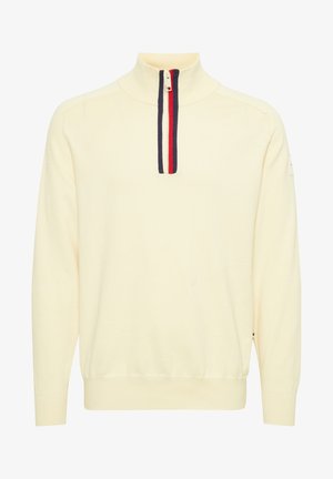 Krem pulover s ovratnikom na pol zadrgo. Ima kontrastni navpični trak v mornarsko modri, rdeči in beli barvi. Pleteno blago z rebrastimi manšetami.