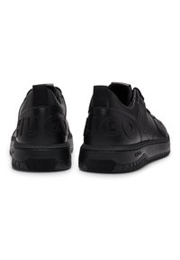 Svarta lädersneakers med en strukturerad yta, med en upphöjd "HUGO"-logotyp på hälen, en stabil sula och elastiska dragremmar bak.