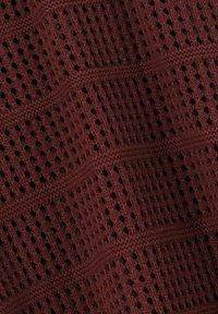 Bordeaux-farbener Strickstoff mit einem strukturierten, offenen Webmuster, das diagonale Linien und kleine Löcher zur Belüftung aufweist.