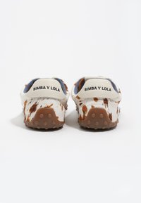 Zapatos de Bimba y Lola con un diseño blanco y marrón moteado, textura suave, cuello acolchado y suela de goma con puntos antideslizantes.