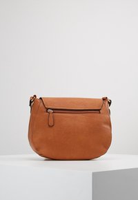 Skórzana torba na ramię w kolorze jasnobrązowym o zaokrąglonym kształcie, z przednią kieszenią na zamek i regulowanym paskiem. Gładka faktura z minimalistycznym wzornictwem.