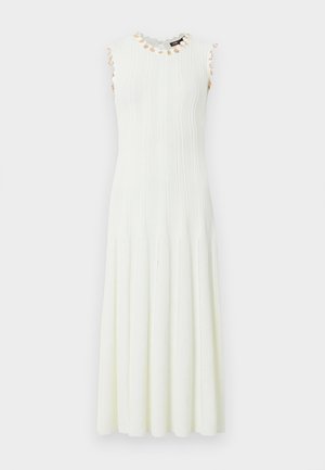 Λευκό μίντι πλεκτό φόρεμα χωρίς μανίκια με κάθετη ανάγλυφη υφή και μικρές μπεζ ανθισμένες διακοσμήσεις γύρω από το ντεκολτέ και τις μασχάλες.