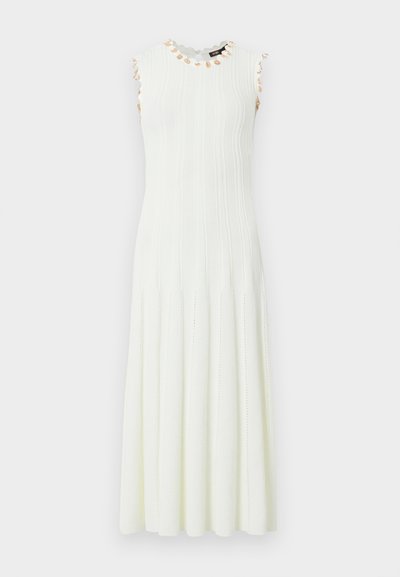 Λευκό μίντι πλεκτό φόρεμα χωρίς μανίκια με κάθετη ανάγλυφη υφή και μικρές μπεζ ανθισμένες διακοσμήσεις γύρω από το ντεκολτέ και τις μασχάλες.