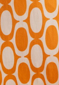 Textil med ett geometriskt mönster av växelvis orange ovaller och vita former, med en mjuk, texturerad tygyta.
