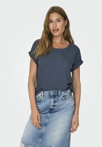 Chemise à manches courtes bleu marine en tissu doux, associée à une jupe en denim bleu clair avec une couture avant et un ourlet effiloché.