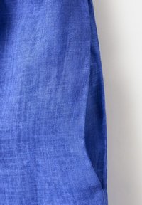 Close-up of textured blue fabric with visible weave pattern, draped against a light background.