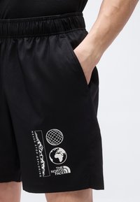 Μαύρα σορτς με ελαστική ζώνη μέσης και πλαϊνή τσέπη, με γραφικά λευκού βουνού, γήινης σφαίρας και λογότυπου The North Face στο αριστερό πόδι.