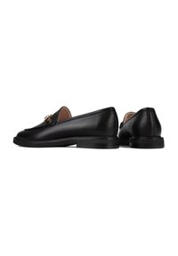 Black leather loafers with a rounded toe, sleek design, gold hardware detail on the front, and a flat rubber sole.