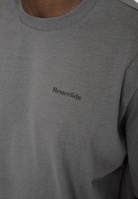 Grå bomuld t-shirt med rund halsudskæring og korte ærmer. Har et diskret sort "Resteröds" logo på venstre side af brystet.